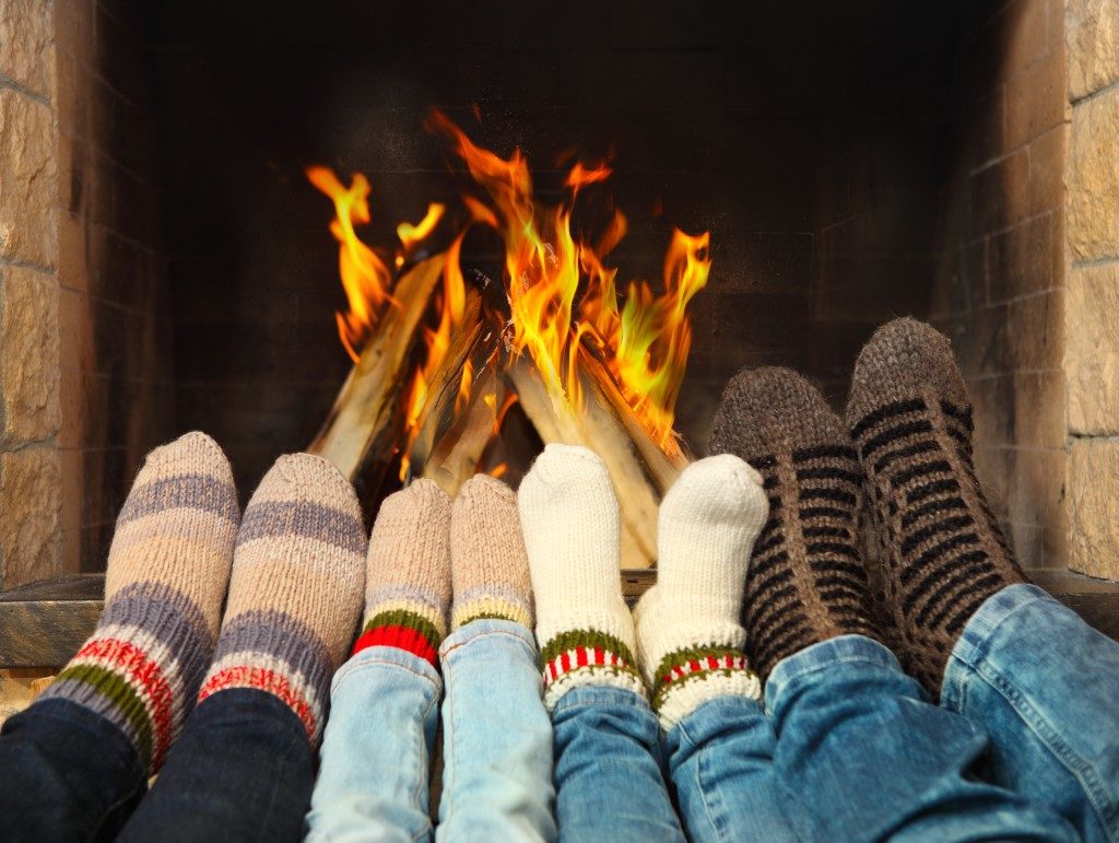 family wearing woolen socks warming near the fireplace