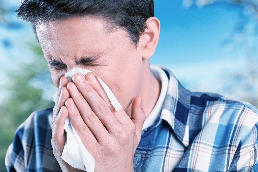 man sneezing into the tissue