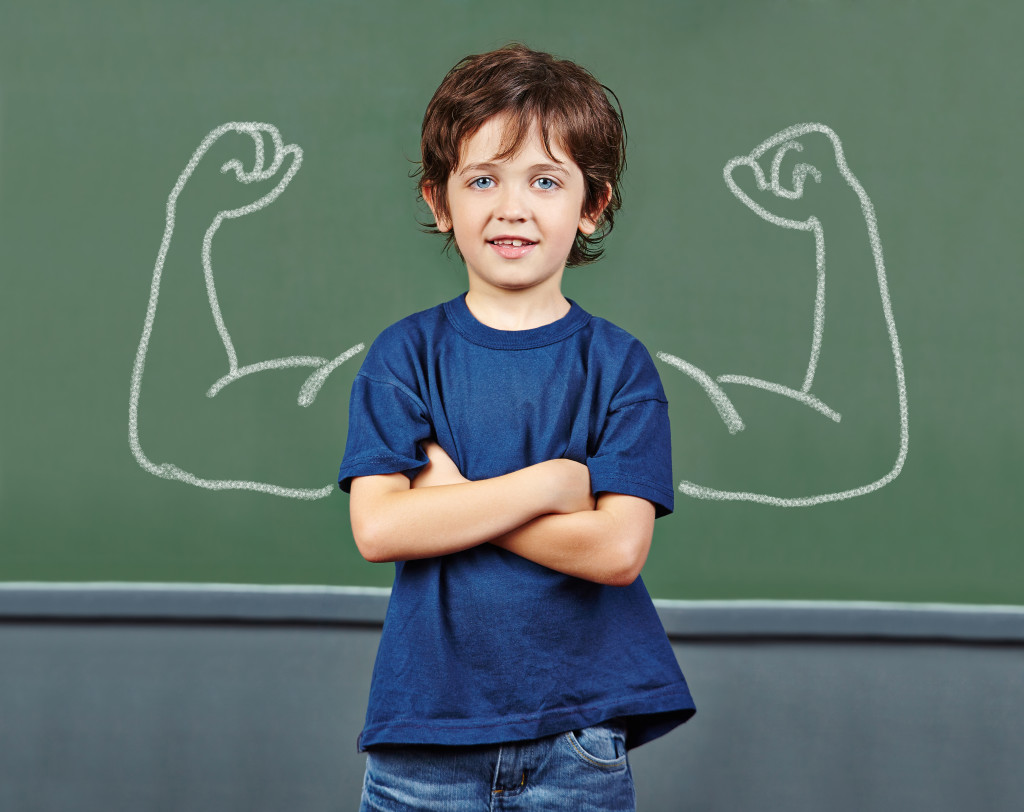 Strong child with muscles drawn on chalkboard
