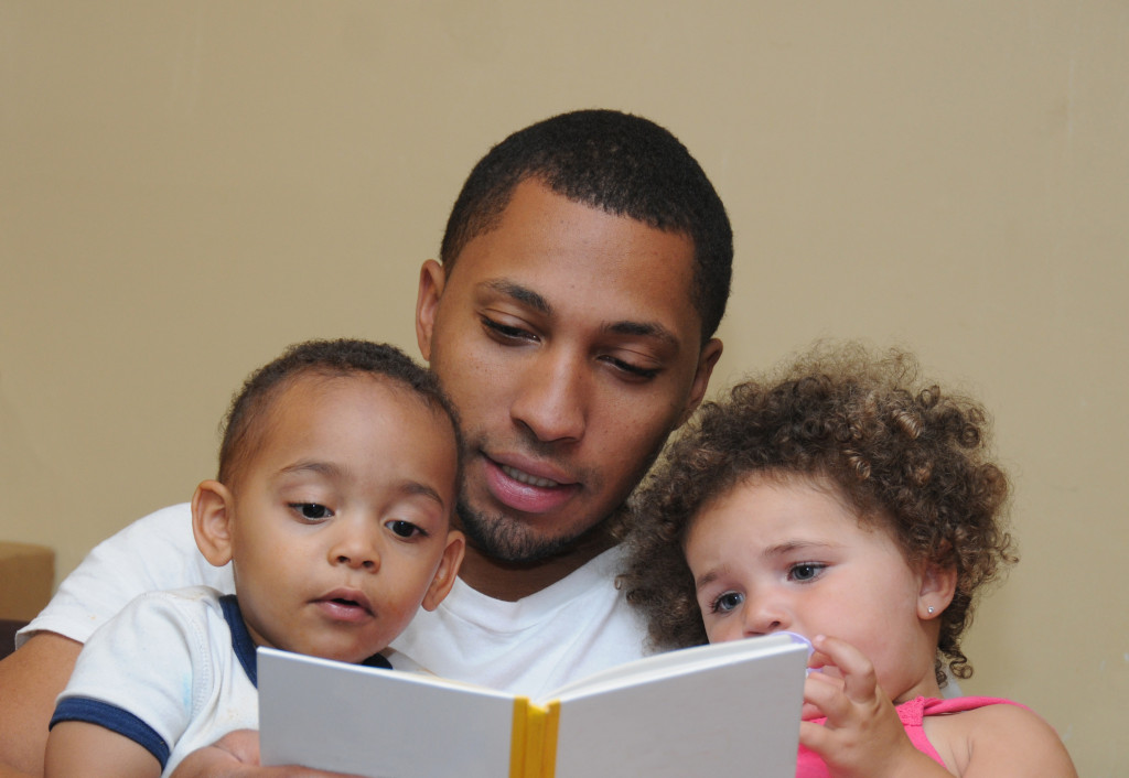 father reading a book to children