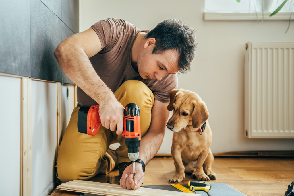 man doing DIY work beside his dog