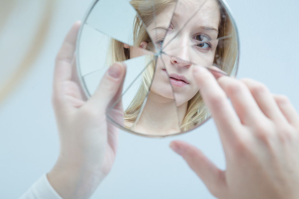 woman touching broken mirror