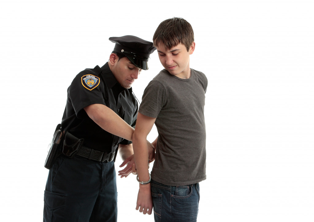 Young teen arrested by a police officer.