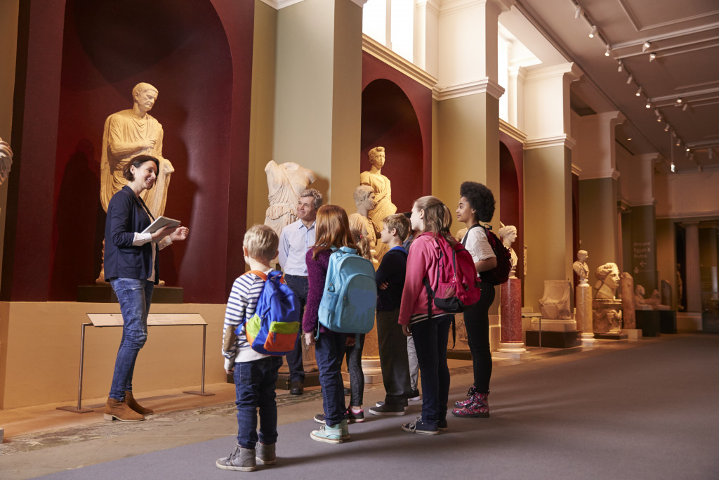 Female guide showing kids art in museum 