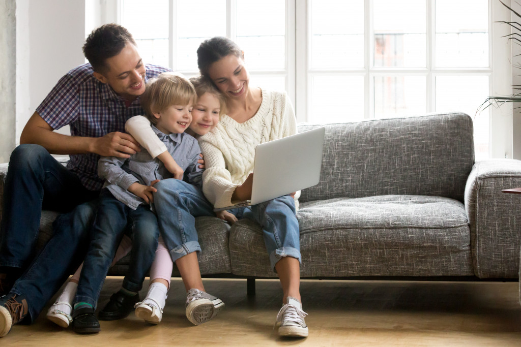 Parents show children a laptop while in living room