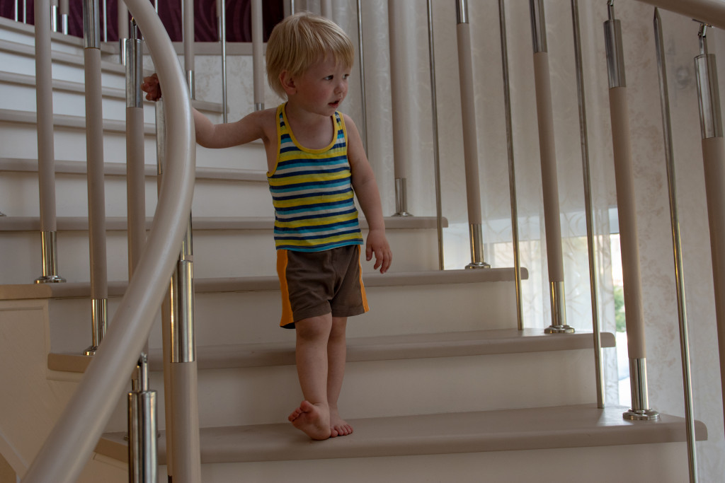 blond kid playing on stairs inside house. Child are happy vacation.
