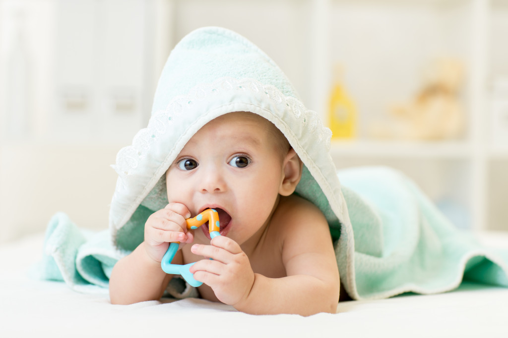 a baby with teether fresh from bath in a nursery