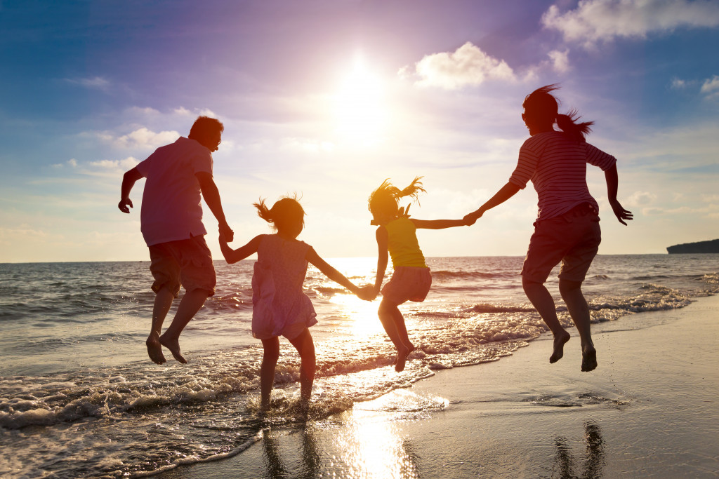 happy family jumping together on the beach while the sun is setting