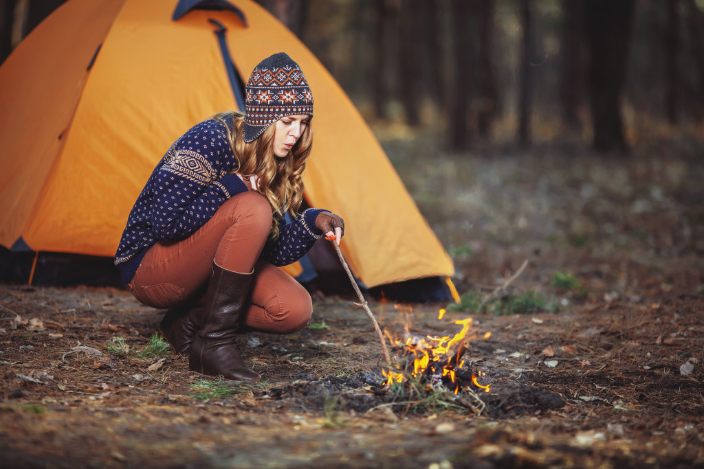 woman making a fire for heating at the camp site