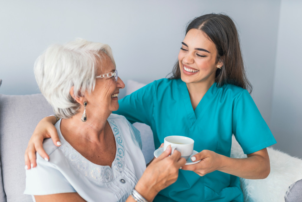 nurse giving tea to her senior patient