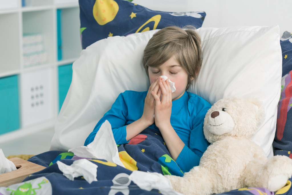 boy blowing his nose sick in bed