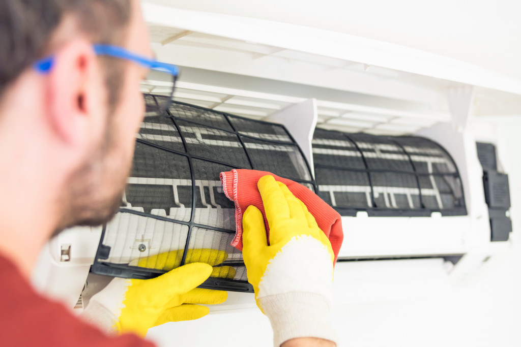 man wearing glasses and gloves cleaning the HVAC filter