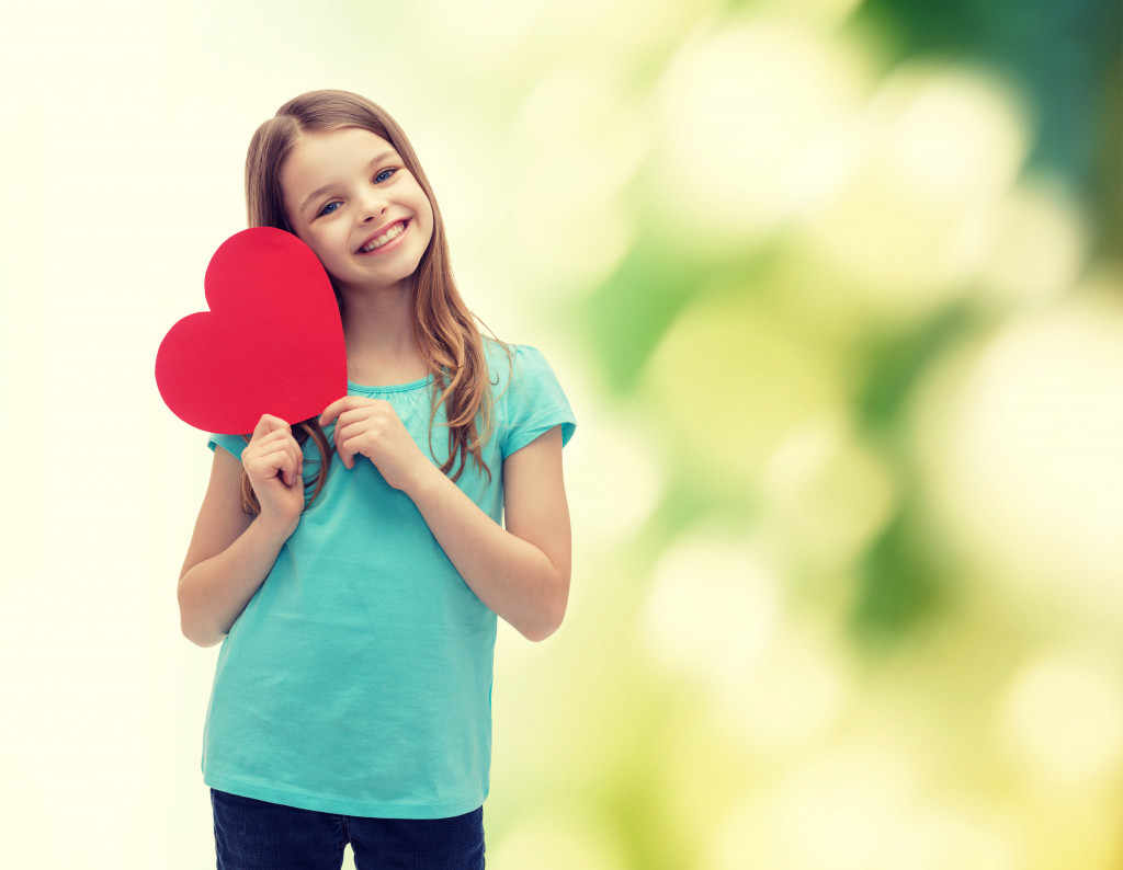 little girl holding a heart-shaped paper