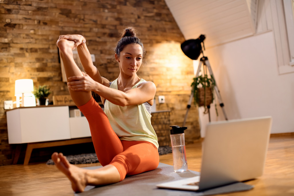 mother doing yoga by following youtube videos with glass bottle on the side