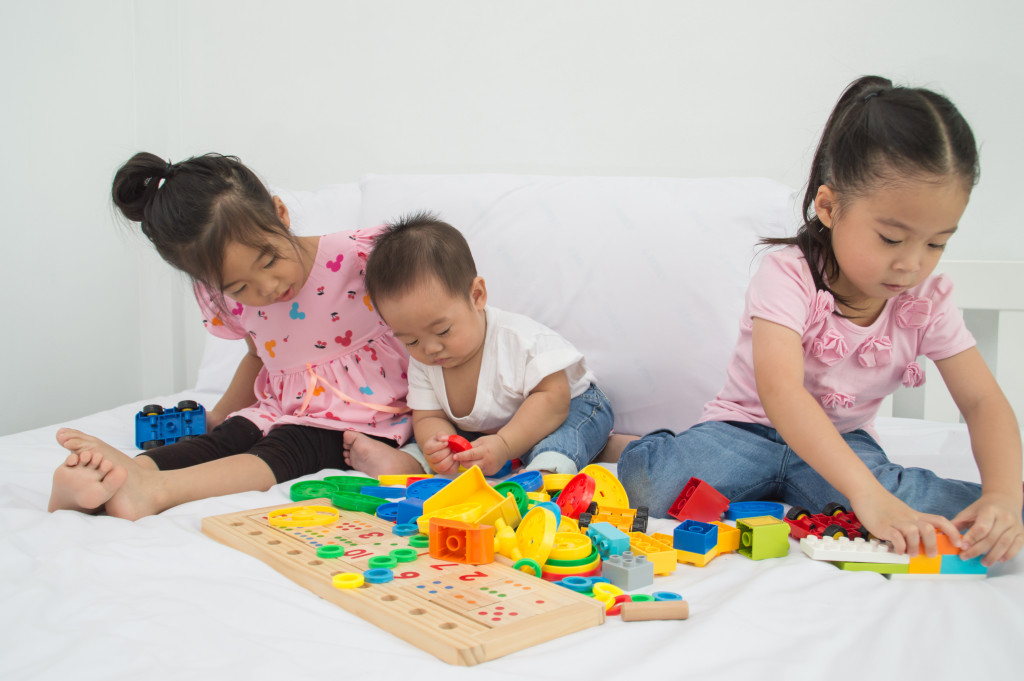Three young children playing in the playroom of a house.