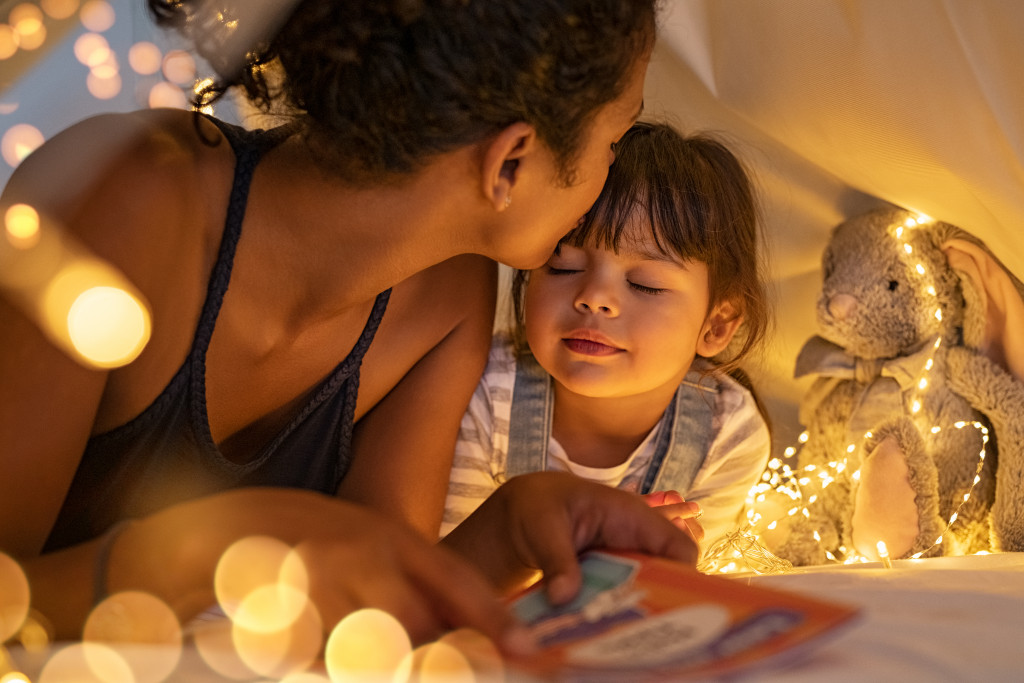 A mother and child in a tent with fairy lights
