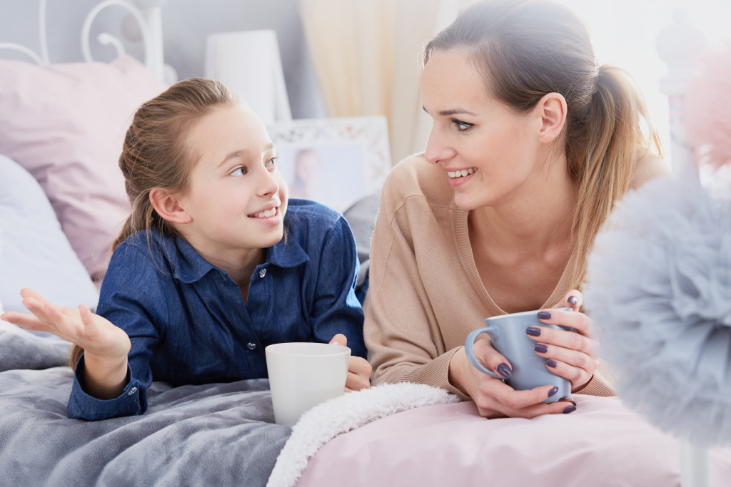 young little girl talking to her mom in bed