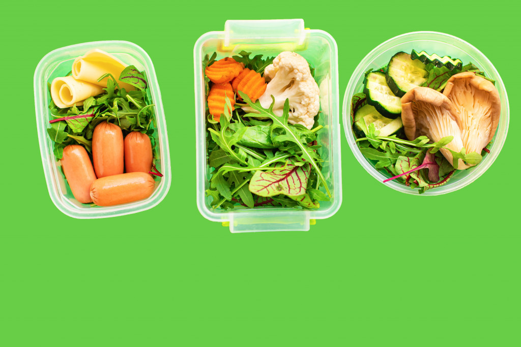 Meal containers with vegetables on a green background