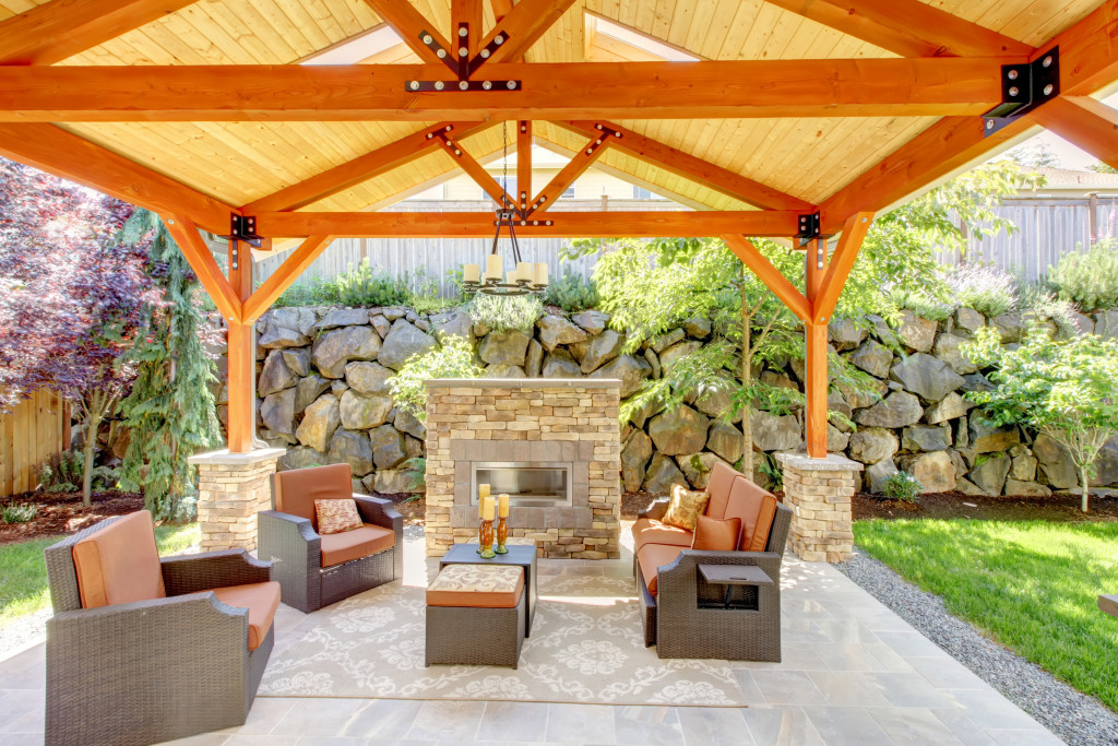 Covered patio with furniture, a fireplace, and wood ceiling.