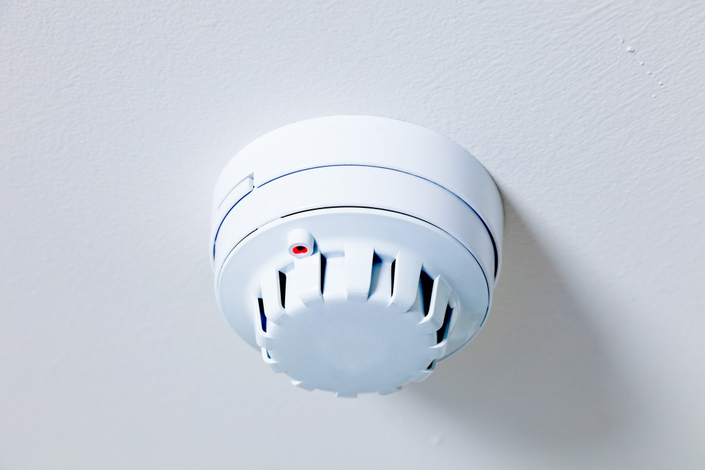A white smoke detector unit on a white ceiling