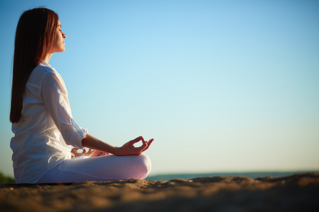 woman quietly meditating outdoors at the sunset
