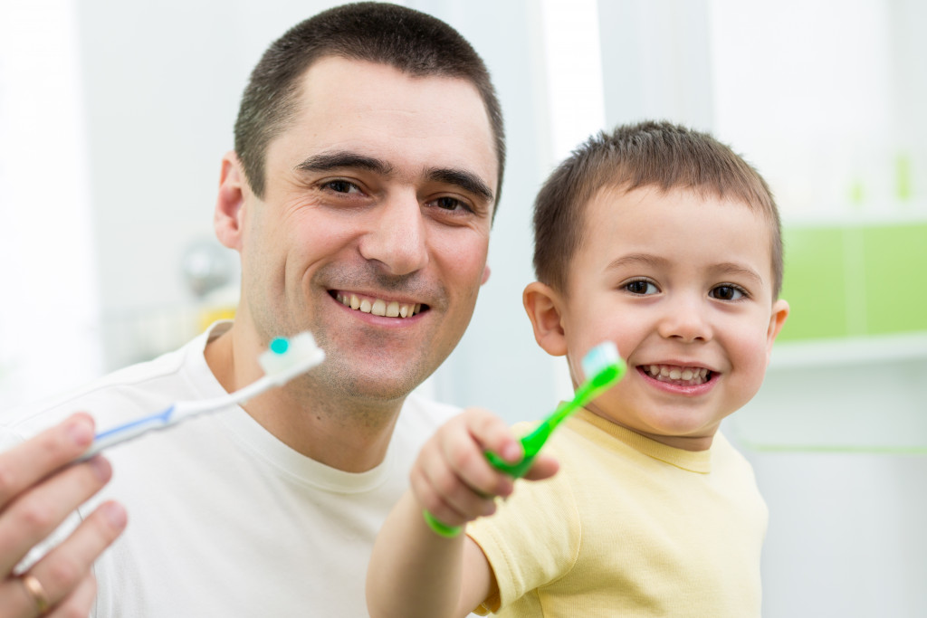 dad teaching son to brush teeth