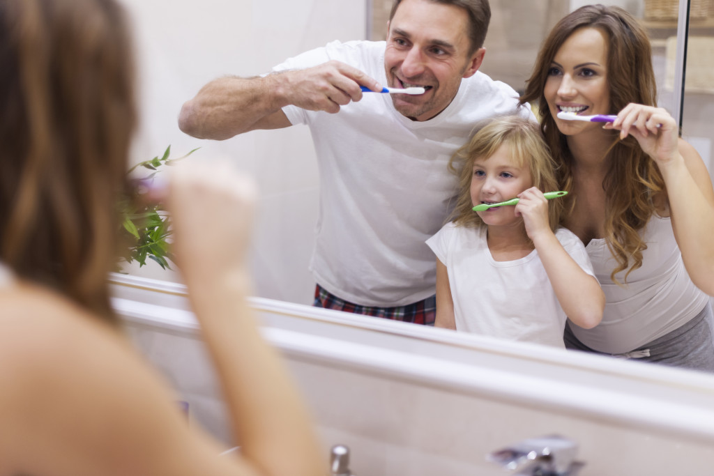 mom and dad with daughter brushing the teeth