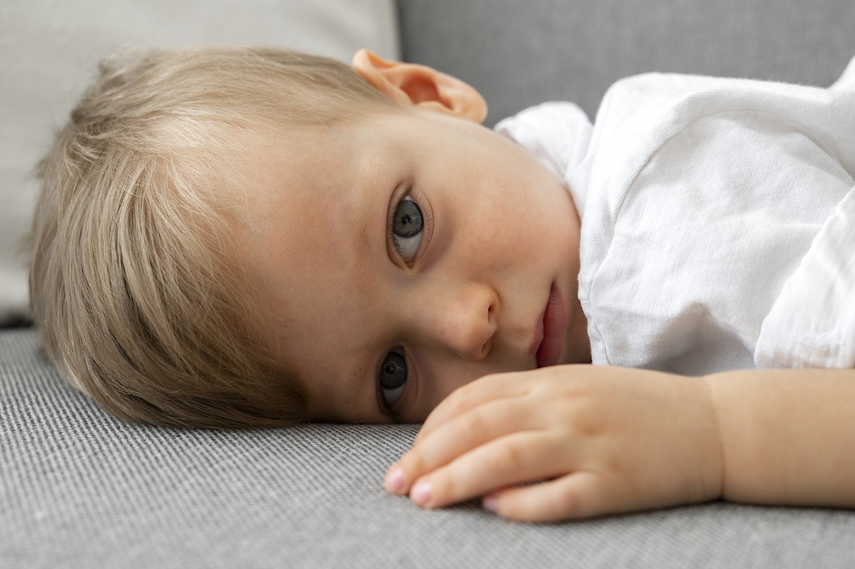 little boy lying on a couch, looking tired