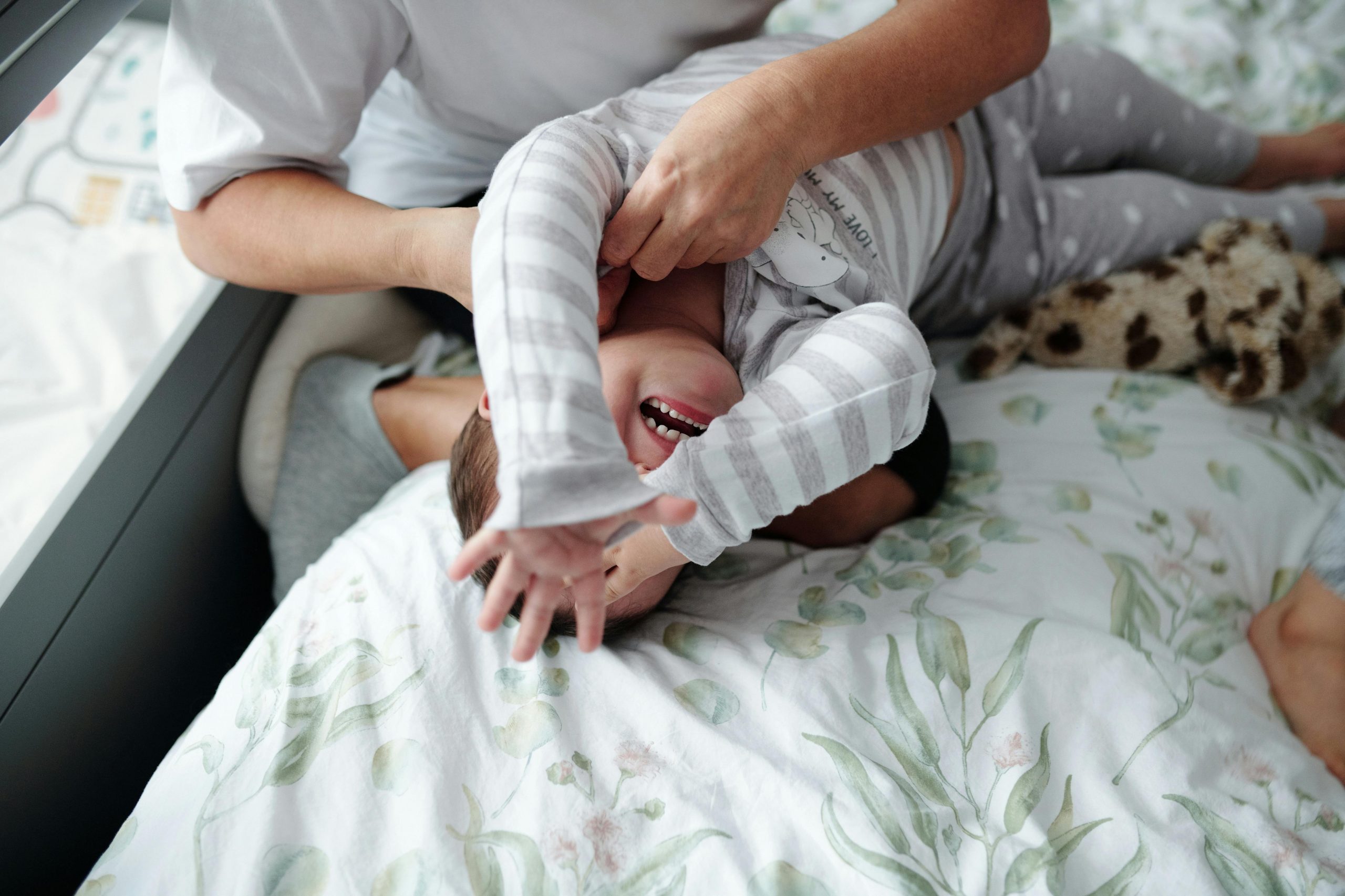 mother holding her crying toddler in bed